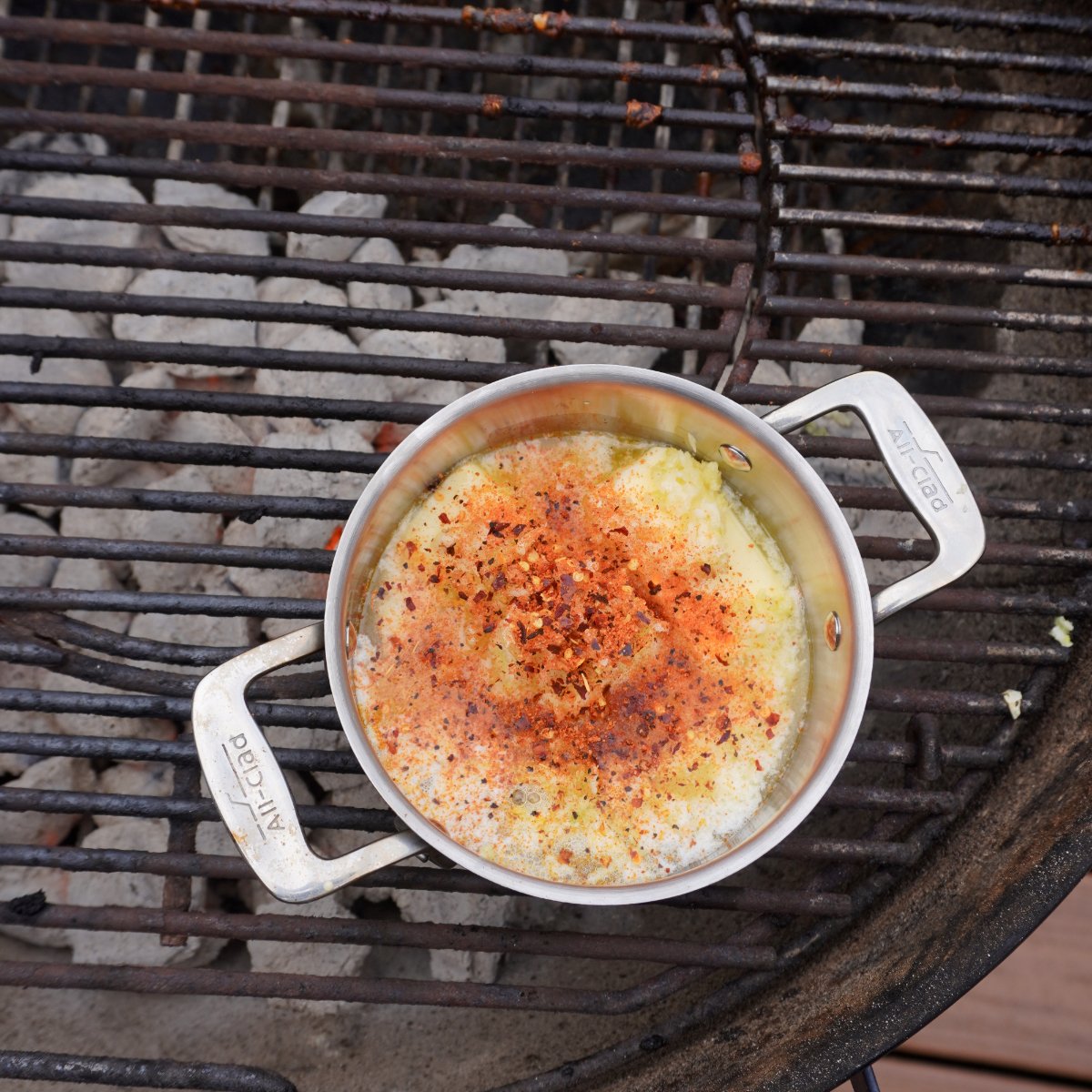 small sauce pan on the grill with garlic parmesan sauce for the wings.