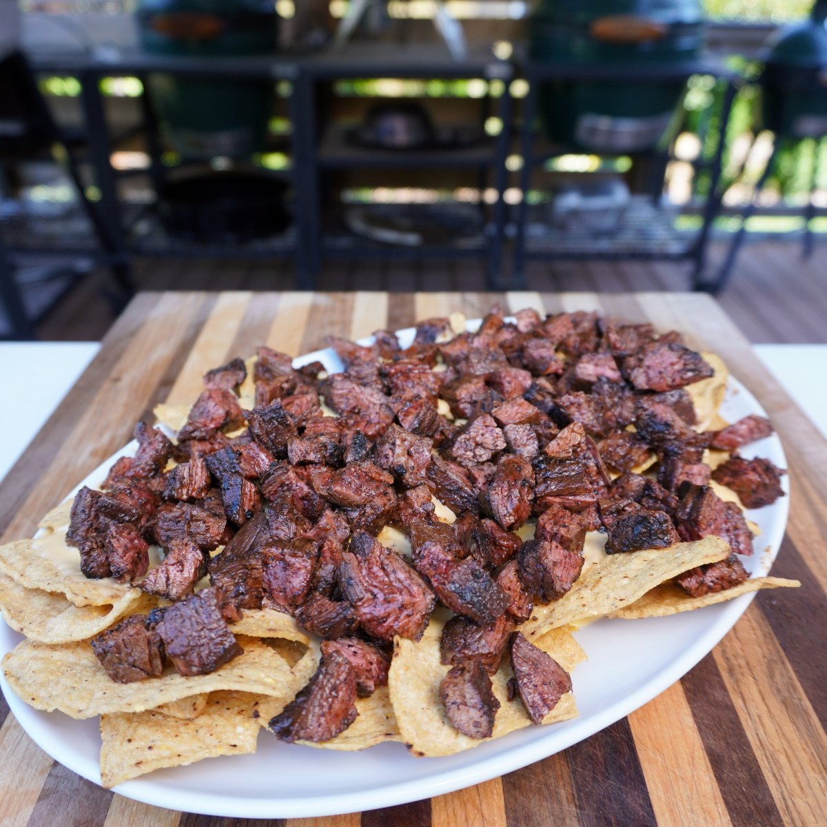 Nacho chips topped with grilled skirt steak on a platter.