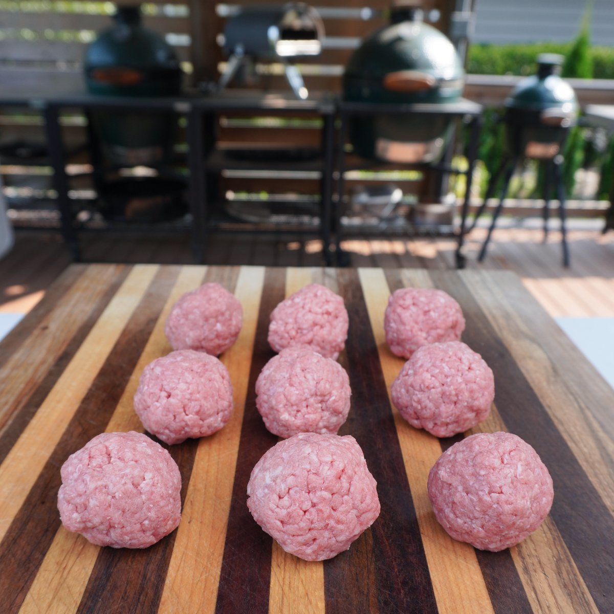Small, evenly shaped round raw beef balls on a cutting board.